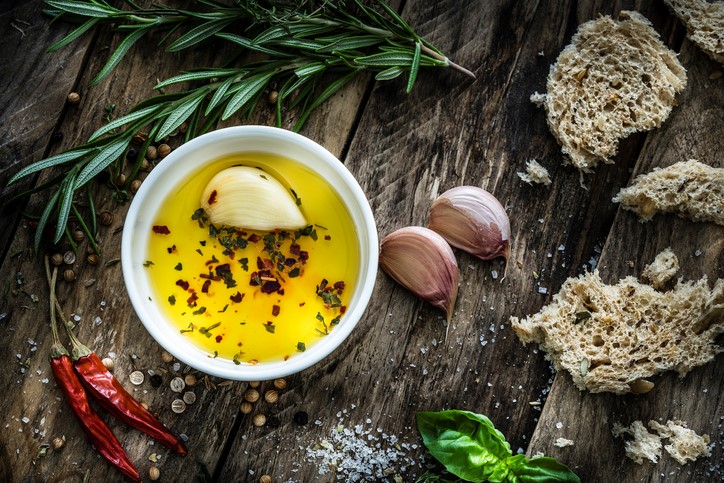 Garlic clove in cup of butter on wood with seasoning